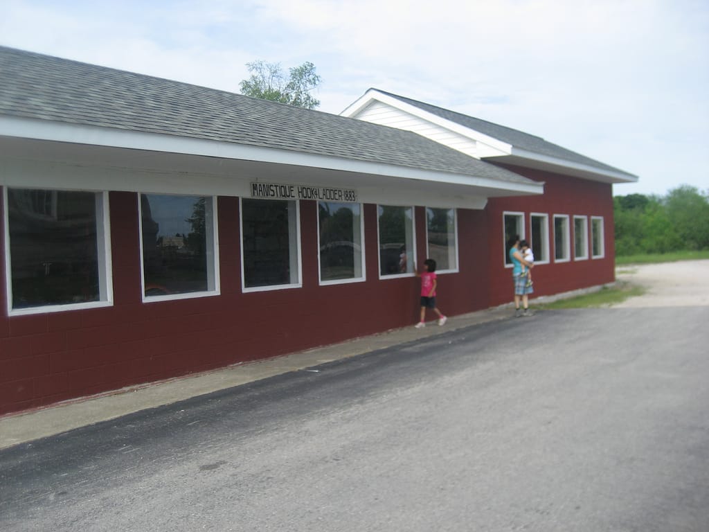 Family standing infront of Manistique hook ladder 1883